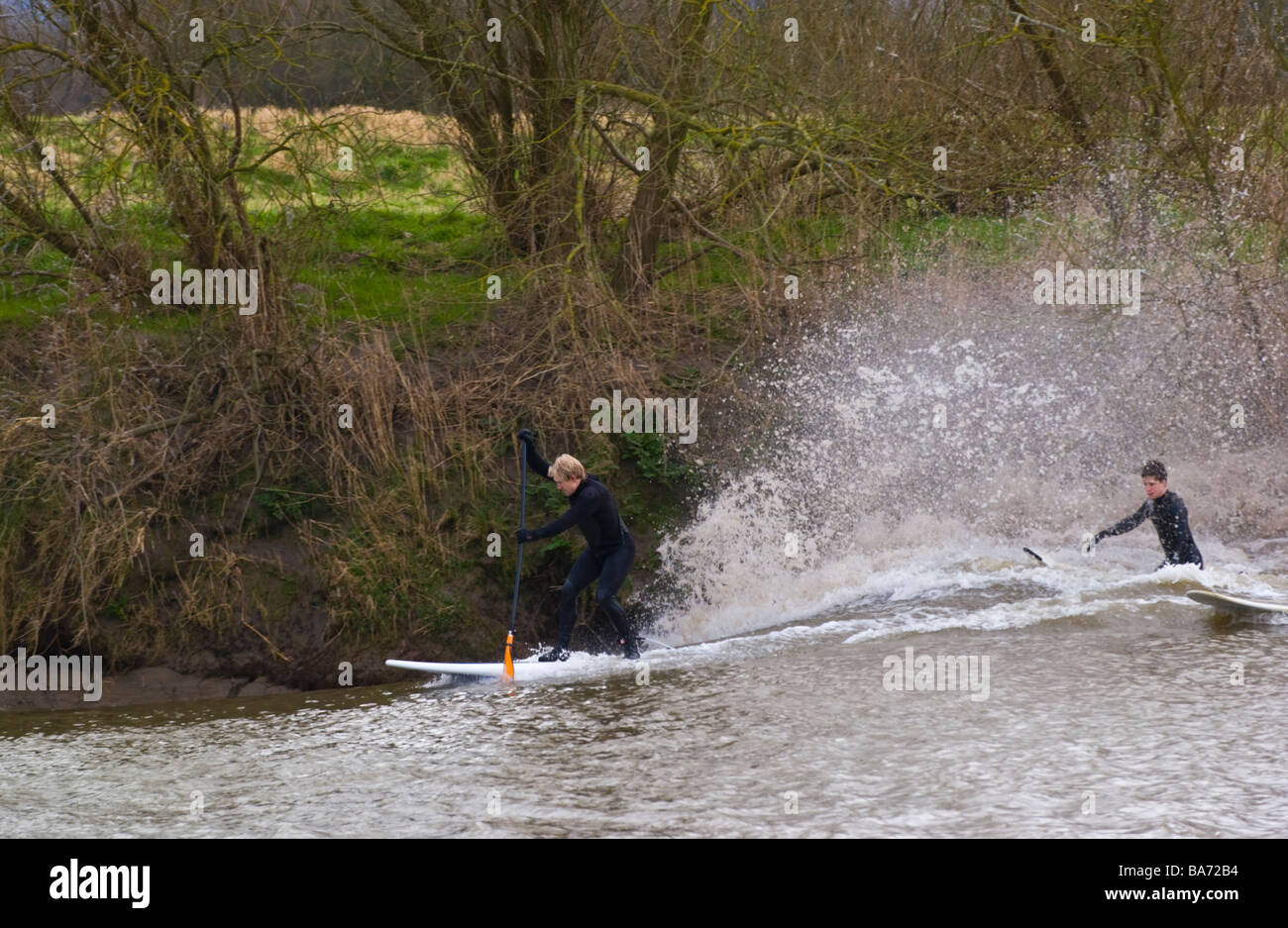 Surfers and canoeists ride the Severn Bore at Minsterworth Gloucestershire England UK Stock Photo