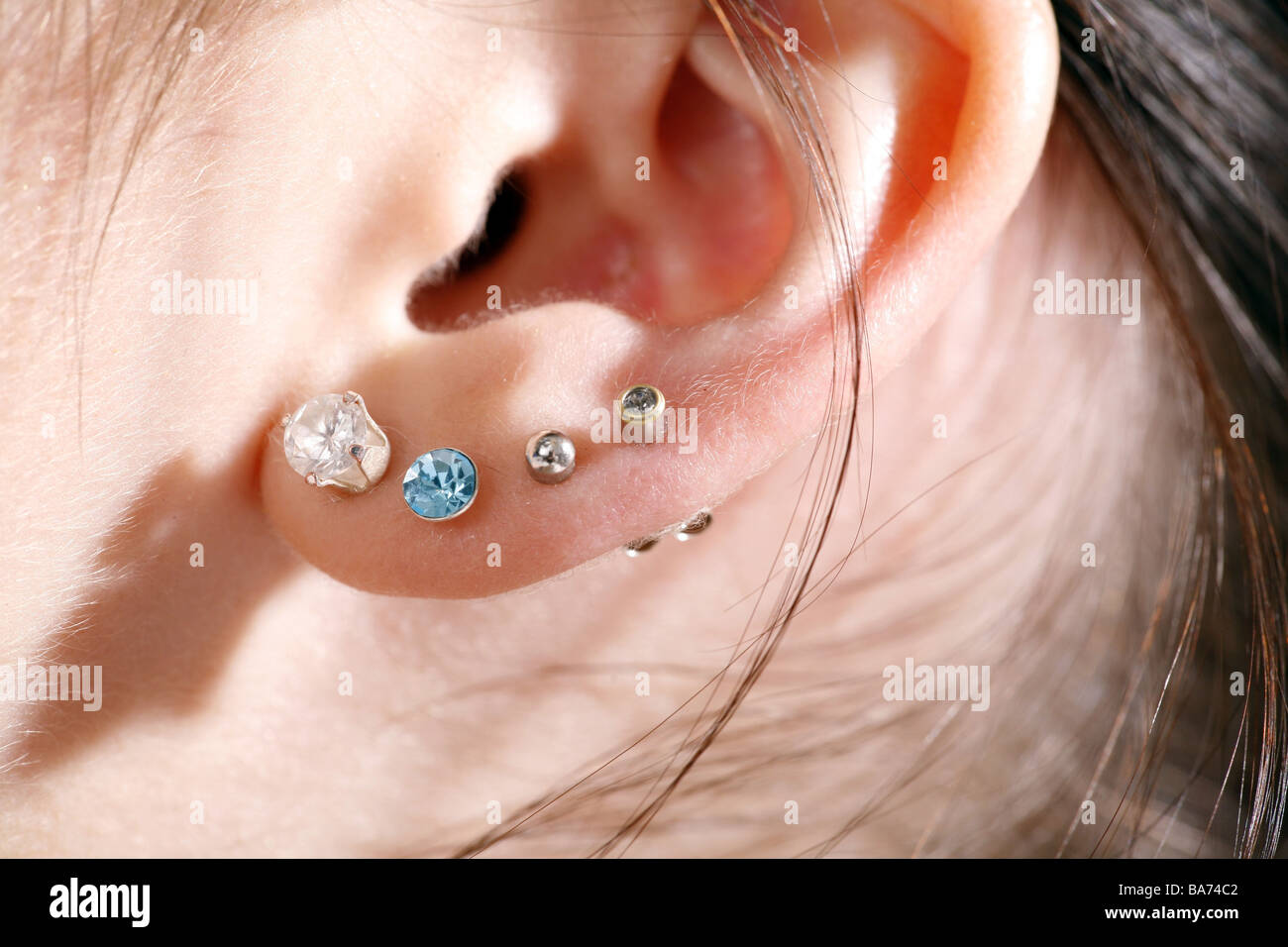 Broached woman young ear studs Stock Photo
