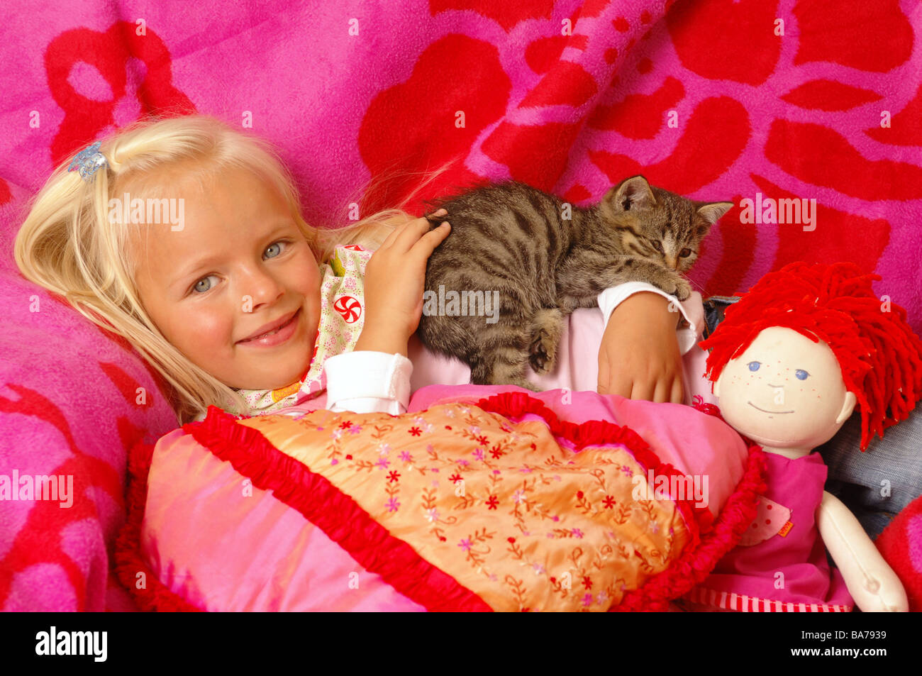 Girls smiles kittens doll cuddle lies portrait series people 5 years child-portrait child toddler blond gaze camera childhood Stock Photo