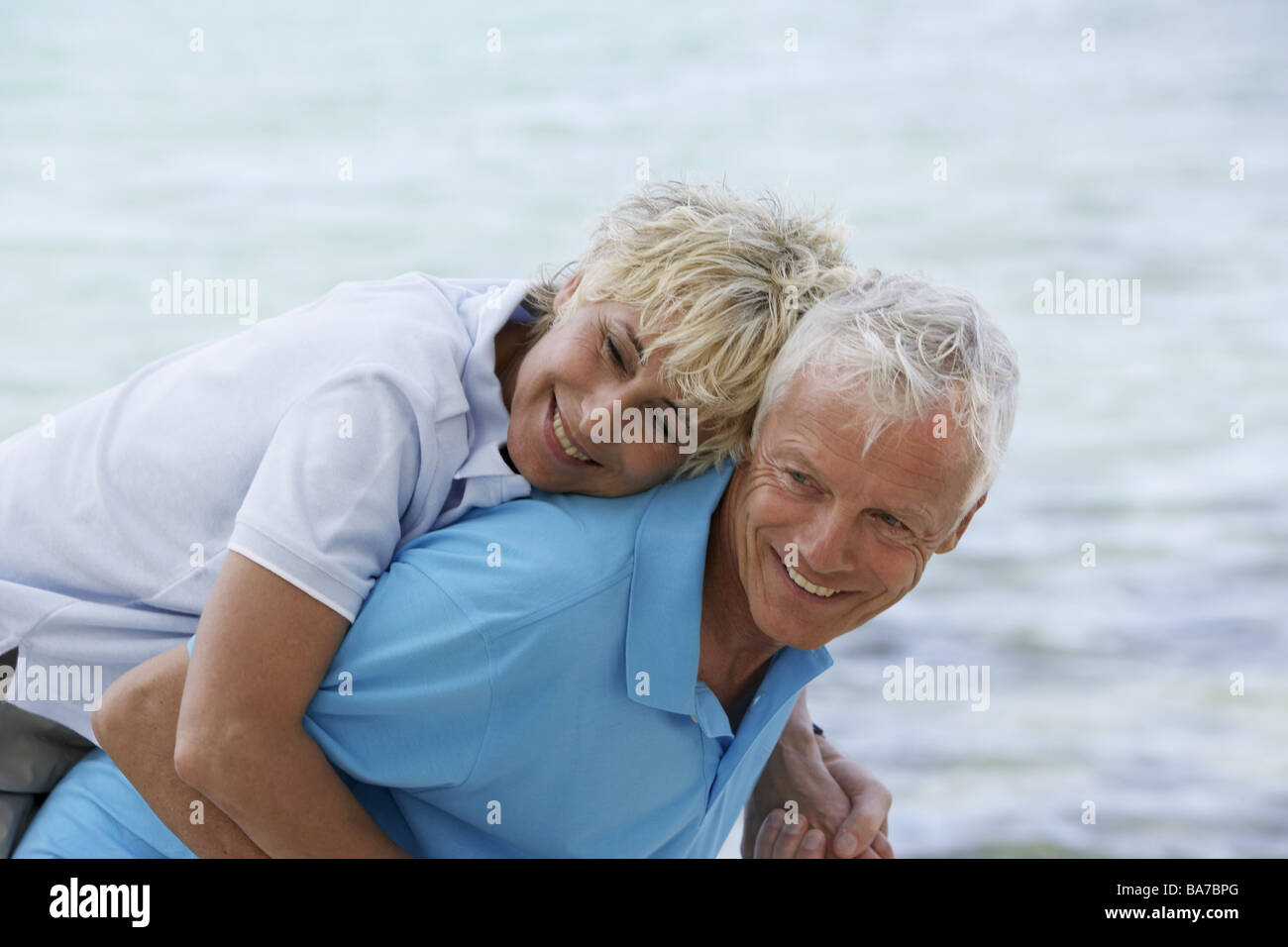 Sandy beach senior-pair piggyback detail series people 50-60 years 60-70 years seniors pair happily joy fun enjoyments Stock Photo