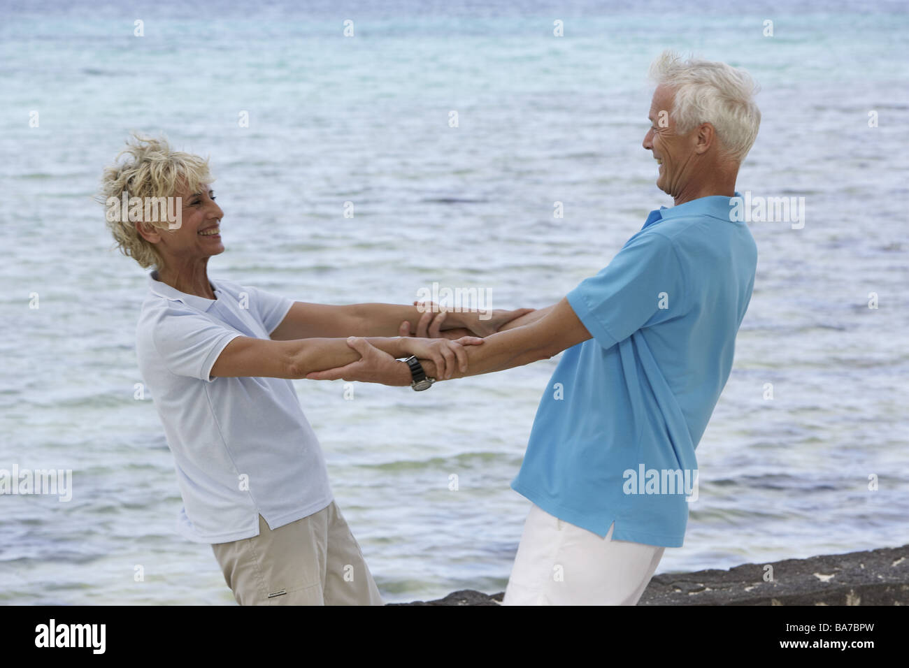 Sandy beach senior-pair movement laughs cheerfully detail series people 50-60 years 60-70 years seniors pair gaze-contact hands Stock Photo