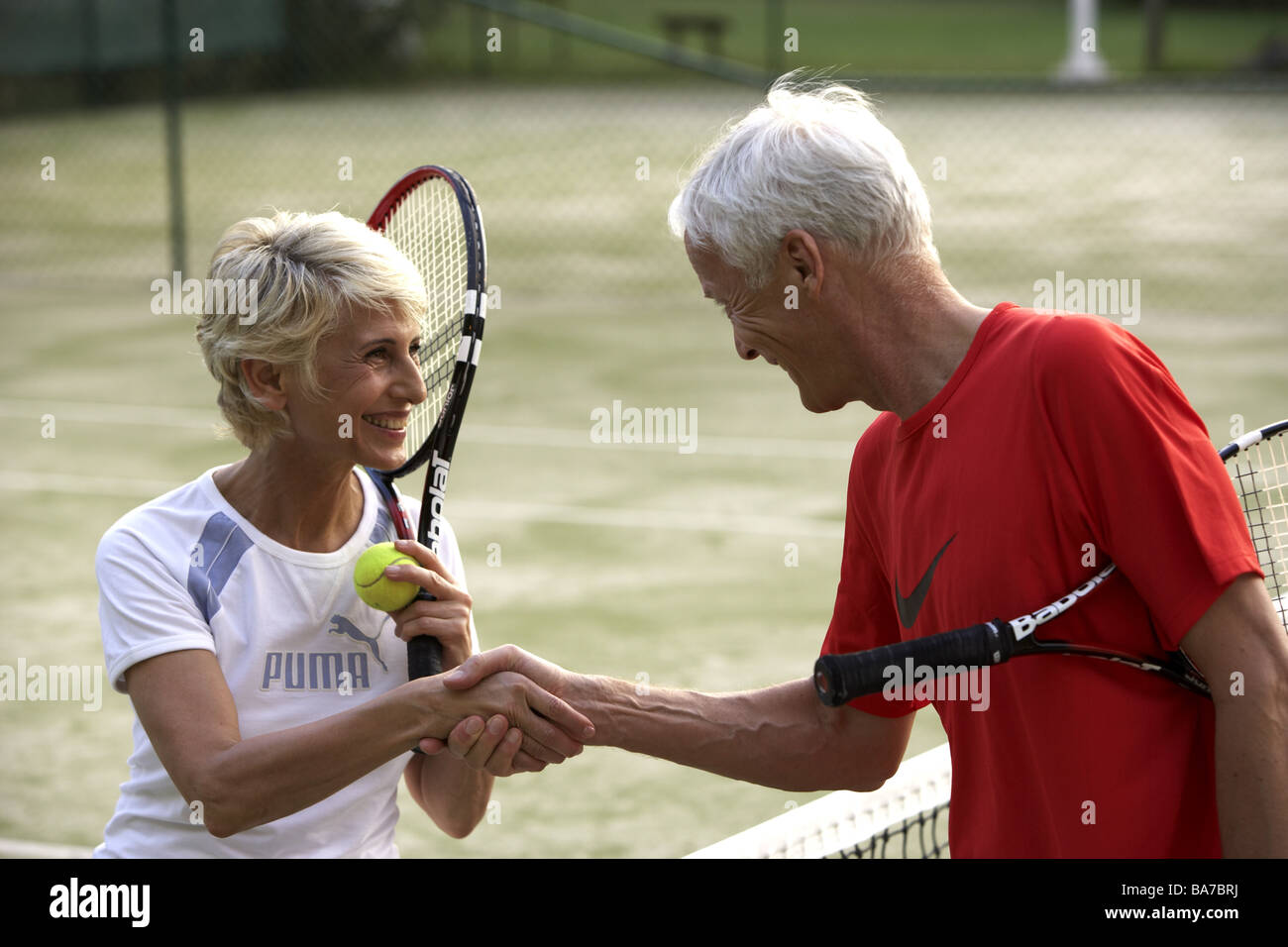 Tennis court senior-pair net handshake cheerfully detail series people 50-60 years 60-70 years seniors pair athletes Stock Photo