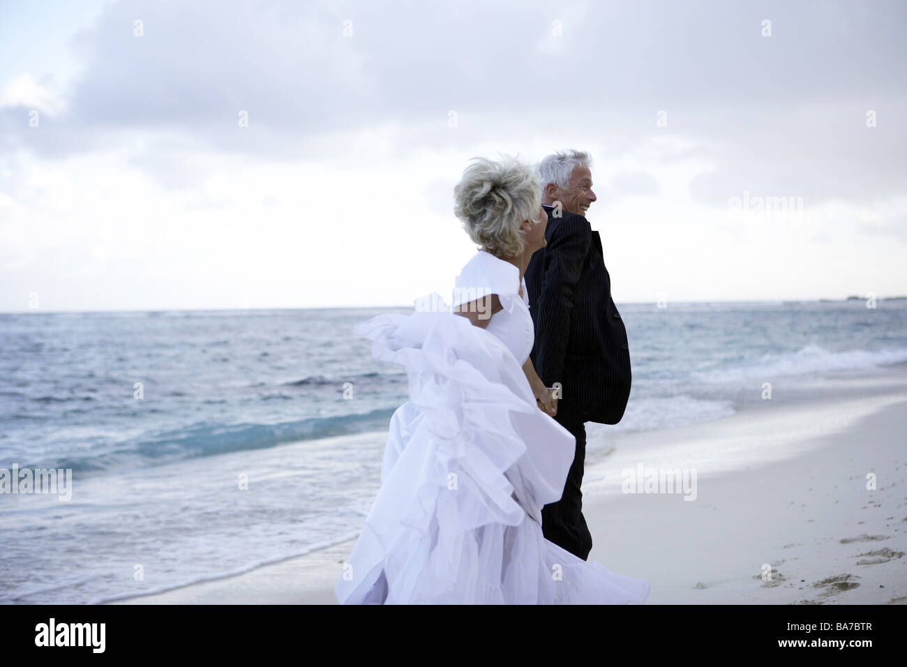 Sandy beach wedding-pair sand runs cheerfully detail series people 50-60 years 60-70 years seniors pair senior-pair wedding Stock Photo