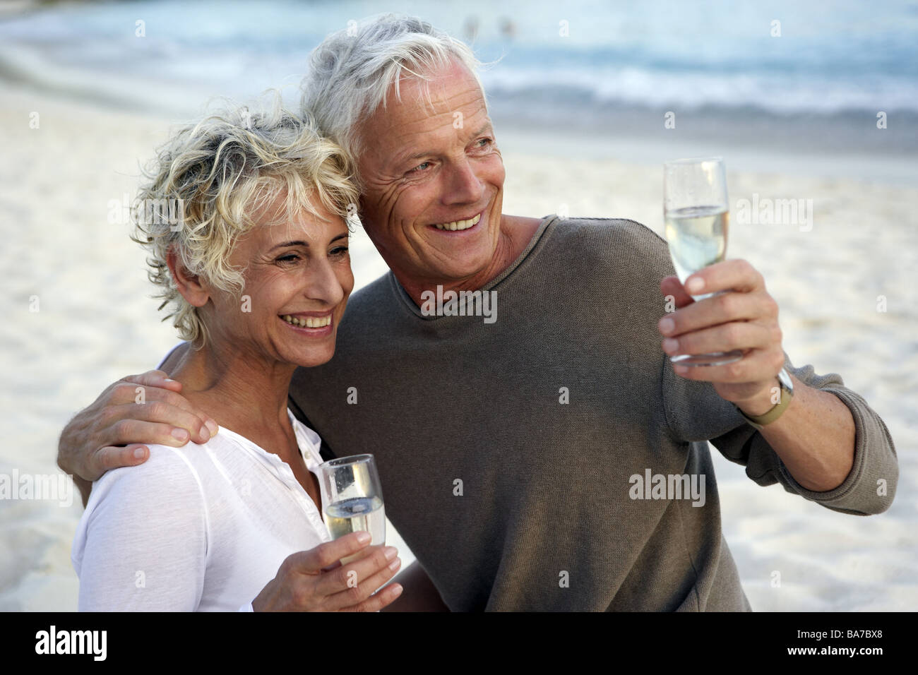 Sandy beach senior-pair champagne drinks cheerfully semi-portrait series people 50-60 years 60-70 years seniors pair beach sand Stock Photo