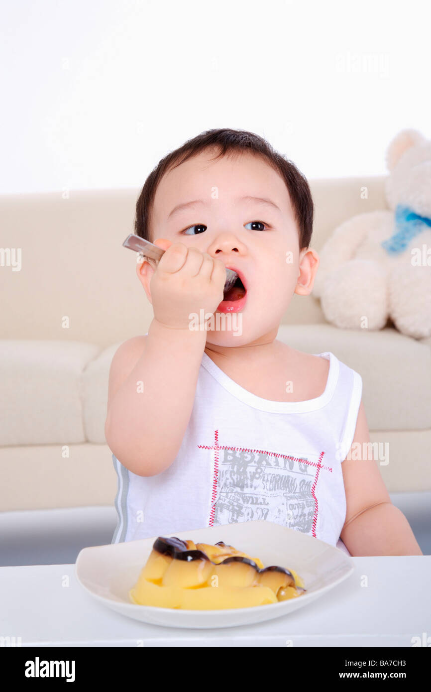 Baby girl putting spoon in mouth portrait close up Stock Photo