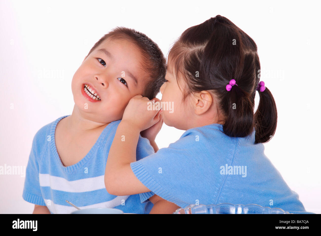 Girl whispering into boy s ear Stock Photo Alamy