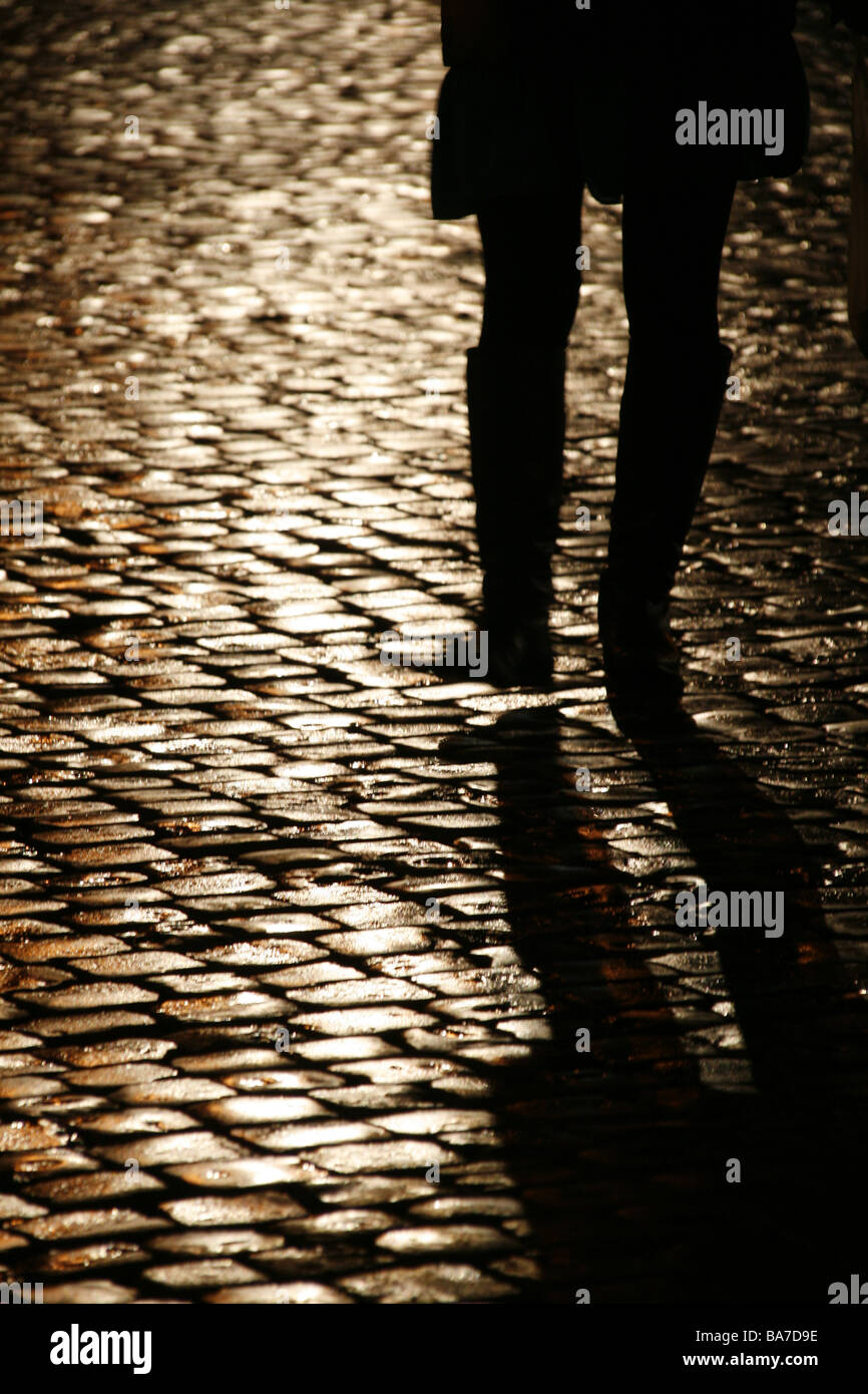 person walking on wet cobbled street at night Stock Photo - Alamy
