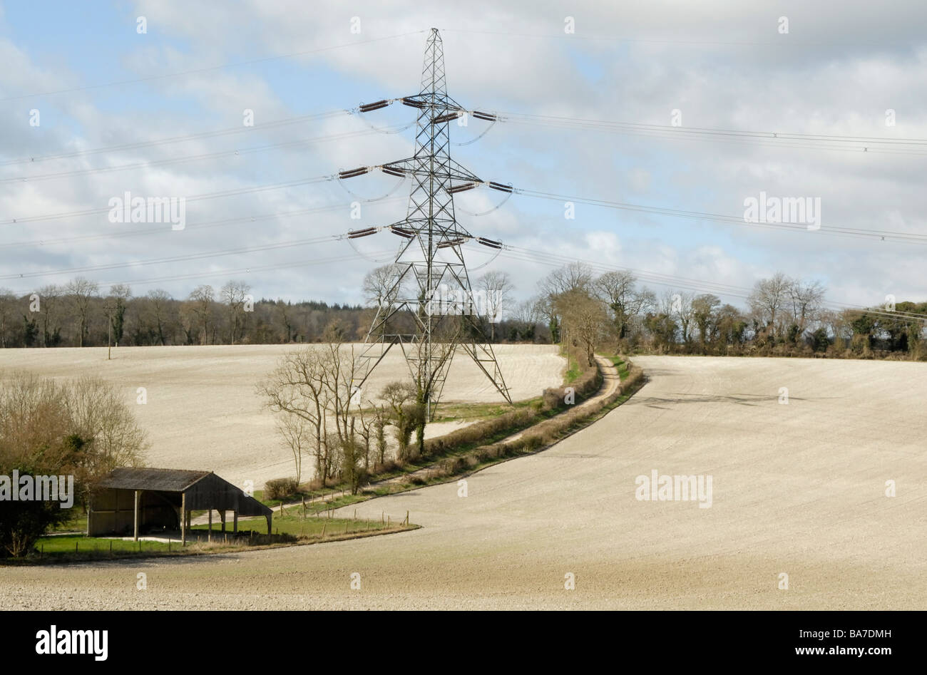 Electricity pylon and cables casting shadows across chalky fields of the South Downs, nr Petersfield, Hampshire, England Stock Photo