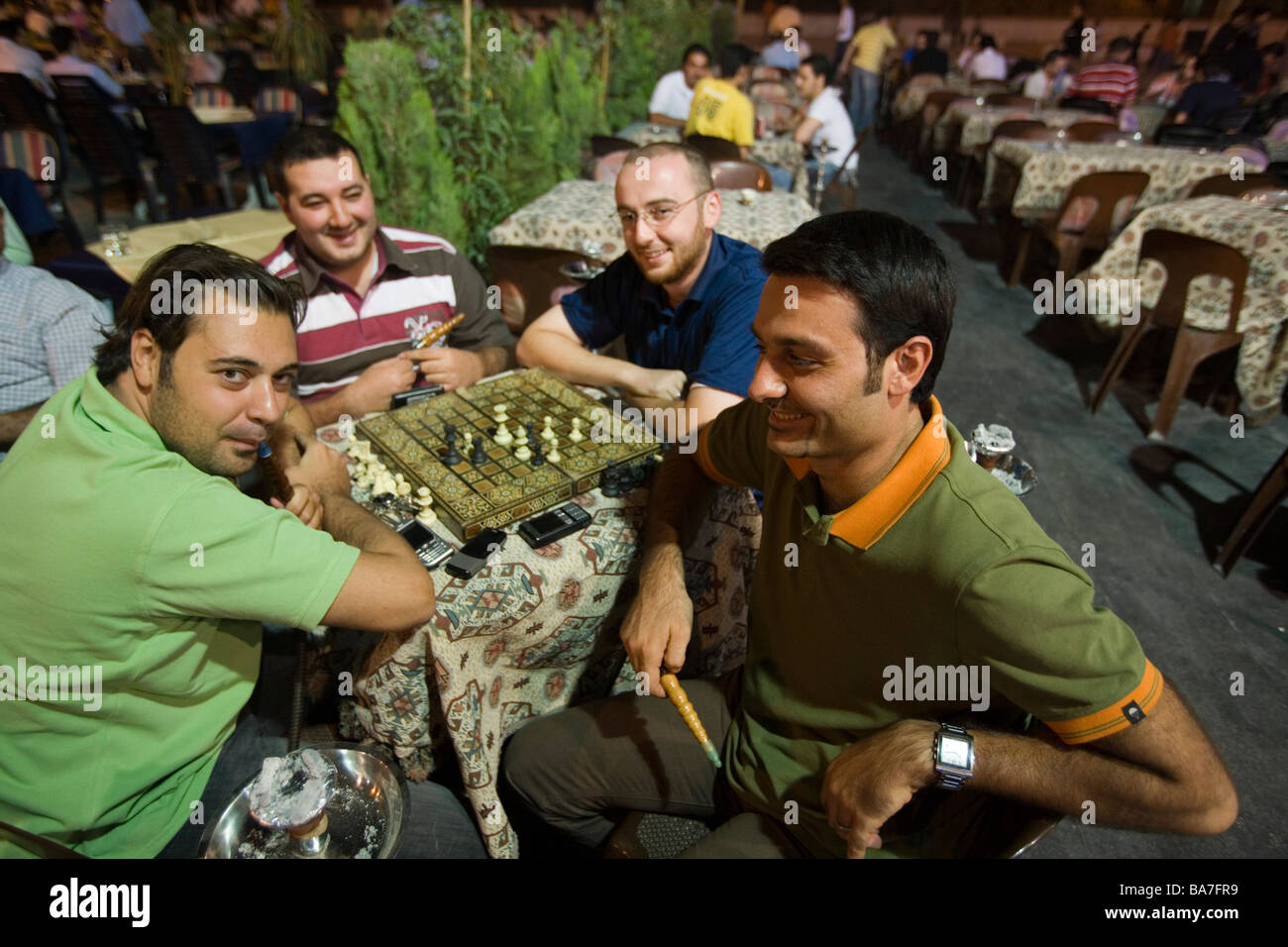 Men playing a game of chess and smoking a Shisha water pipe at an outdoor cafe near the Citadel, Aleppo, Syria, Asia Stock Photo
