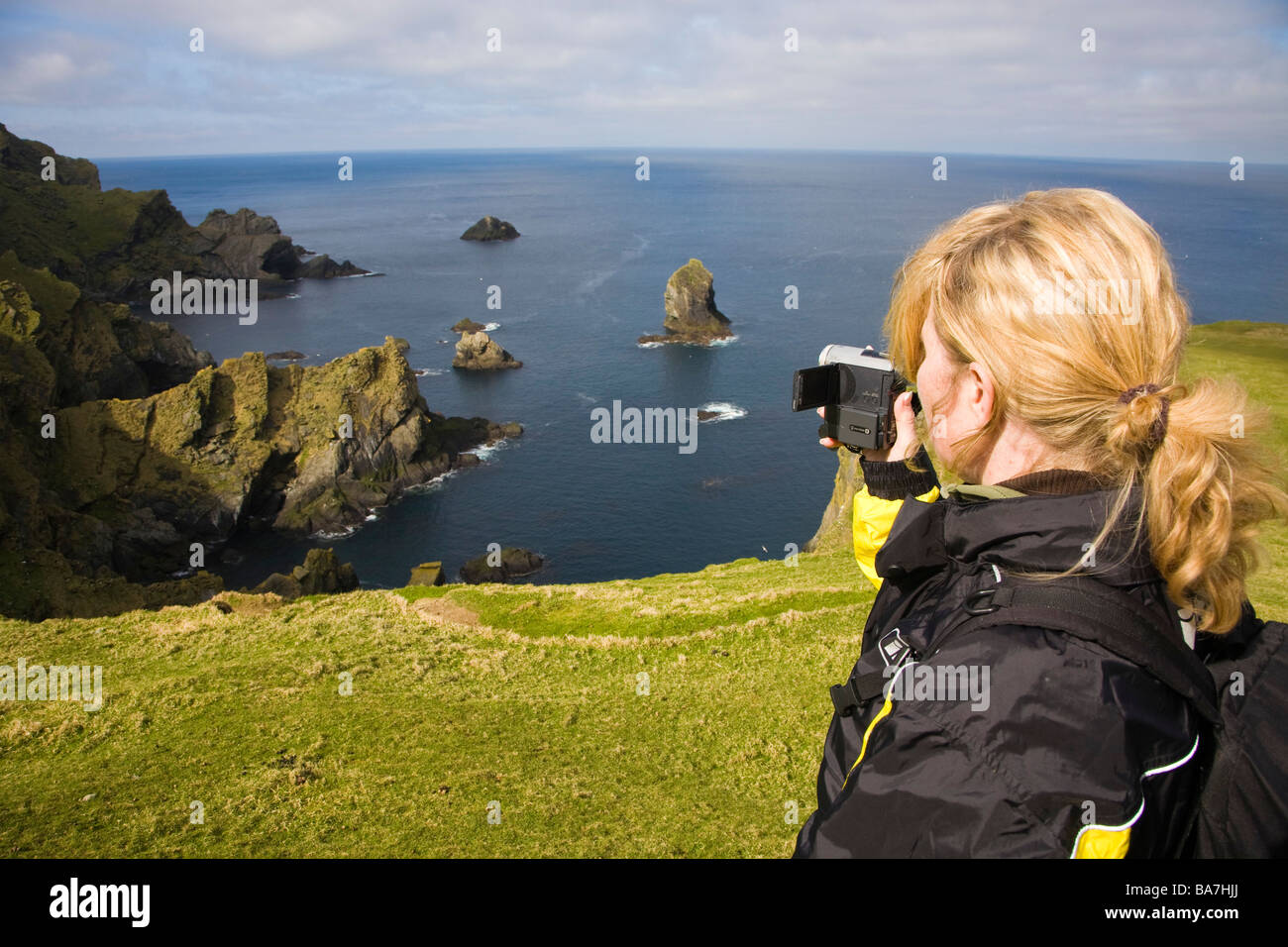 A woman filming the wild coast of Hermaness, Nature Protection Area, island of Unst, Shetland islands, Scotland, Great Britain, Stock Photo