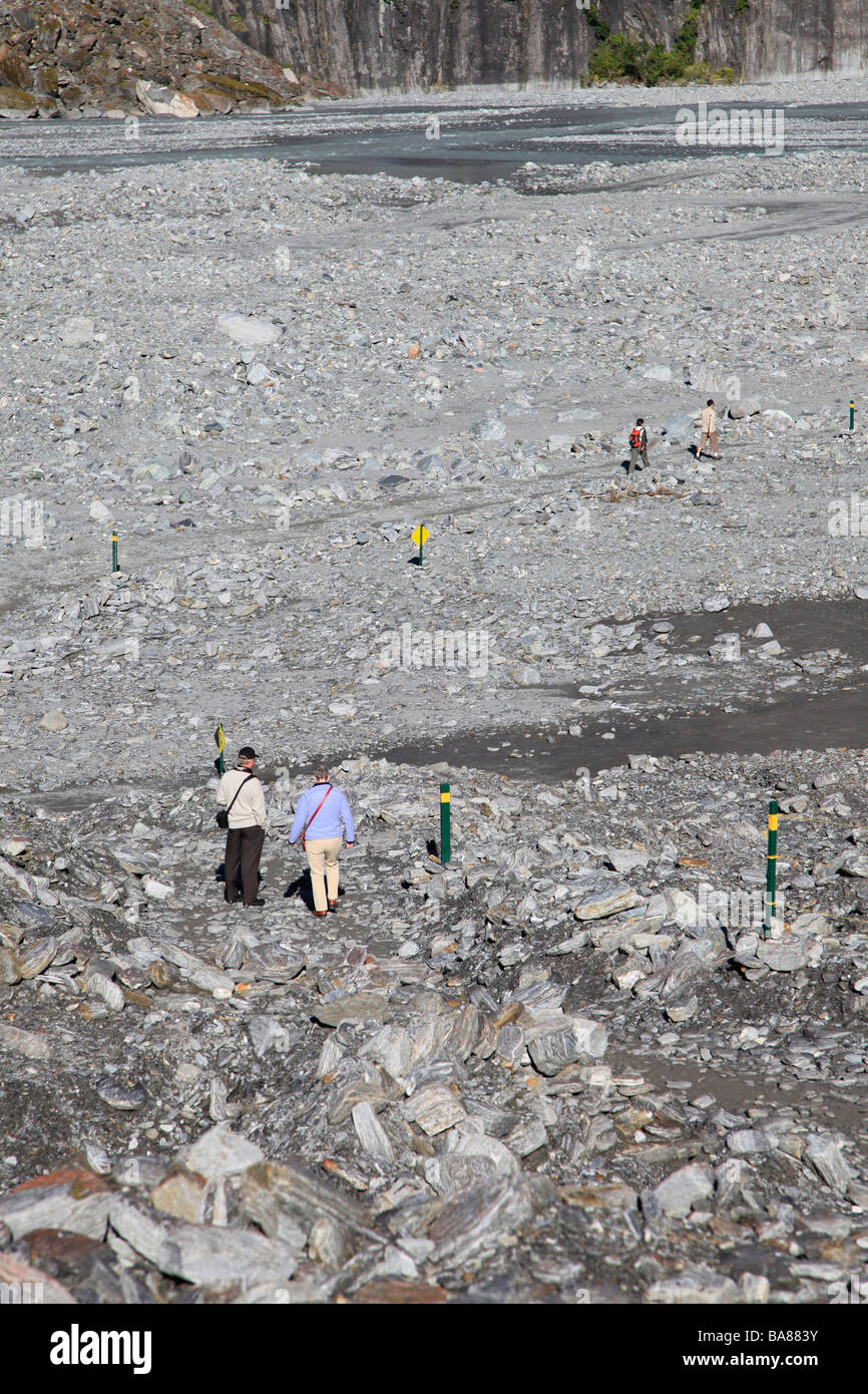 Tourists walking on rocky river bed in glacial valley Stock Photo