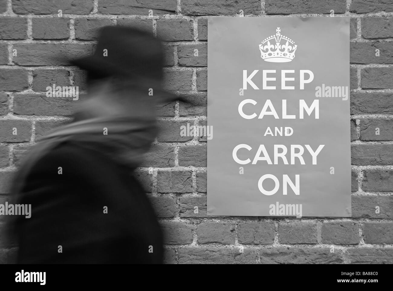 A man walking past a Second World War poster urging people to keep calm and carry on. Stock Photo