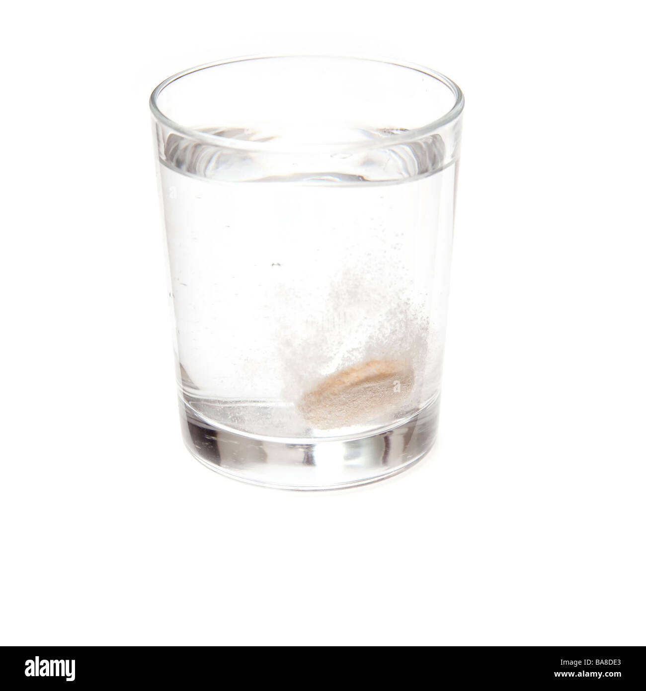 Effervescent vitamin C tablet dissolving in a glass of water. Isolated on a white studio background. Stock Photo