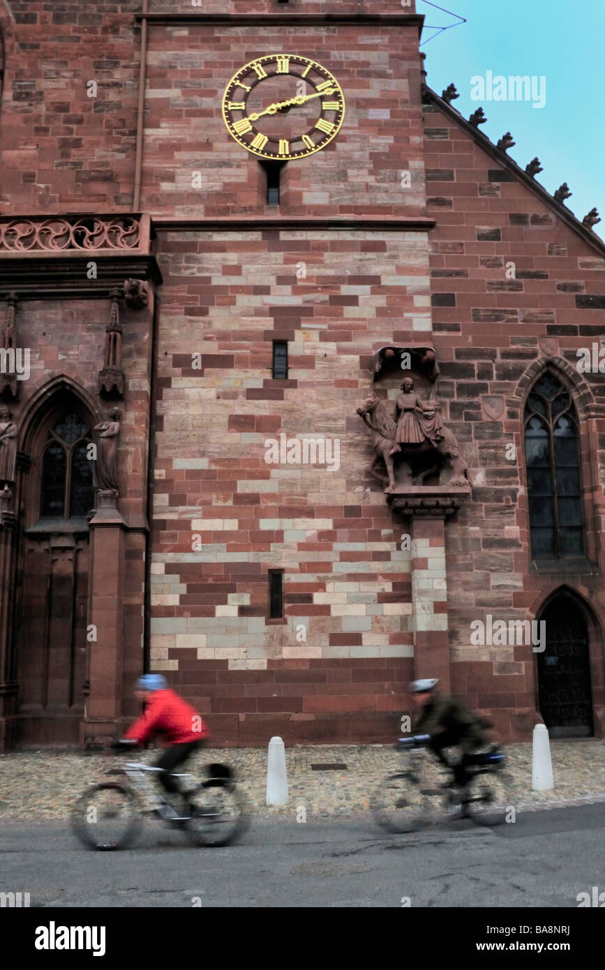 Bicyclists ride past the Basel Cathedral Stock Photo