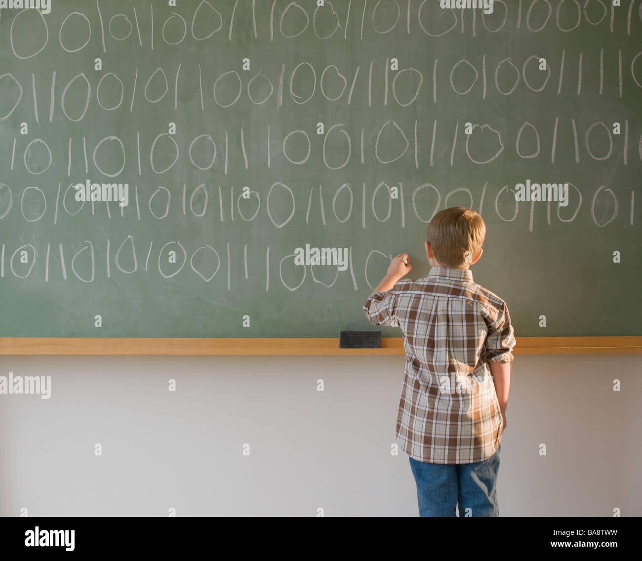 Boy writing binary code on blackboard Stock Photo