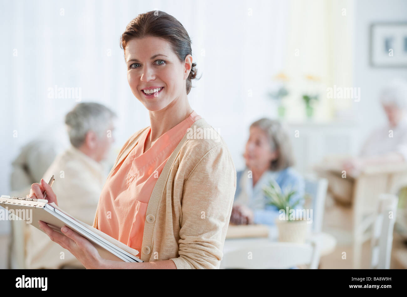 Nurse writing on patient’s medical chart Stock Photo