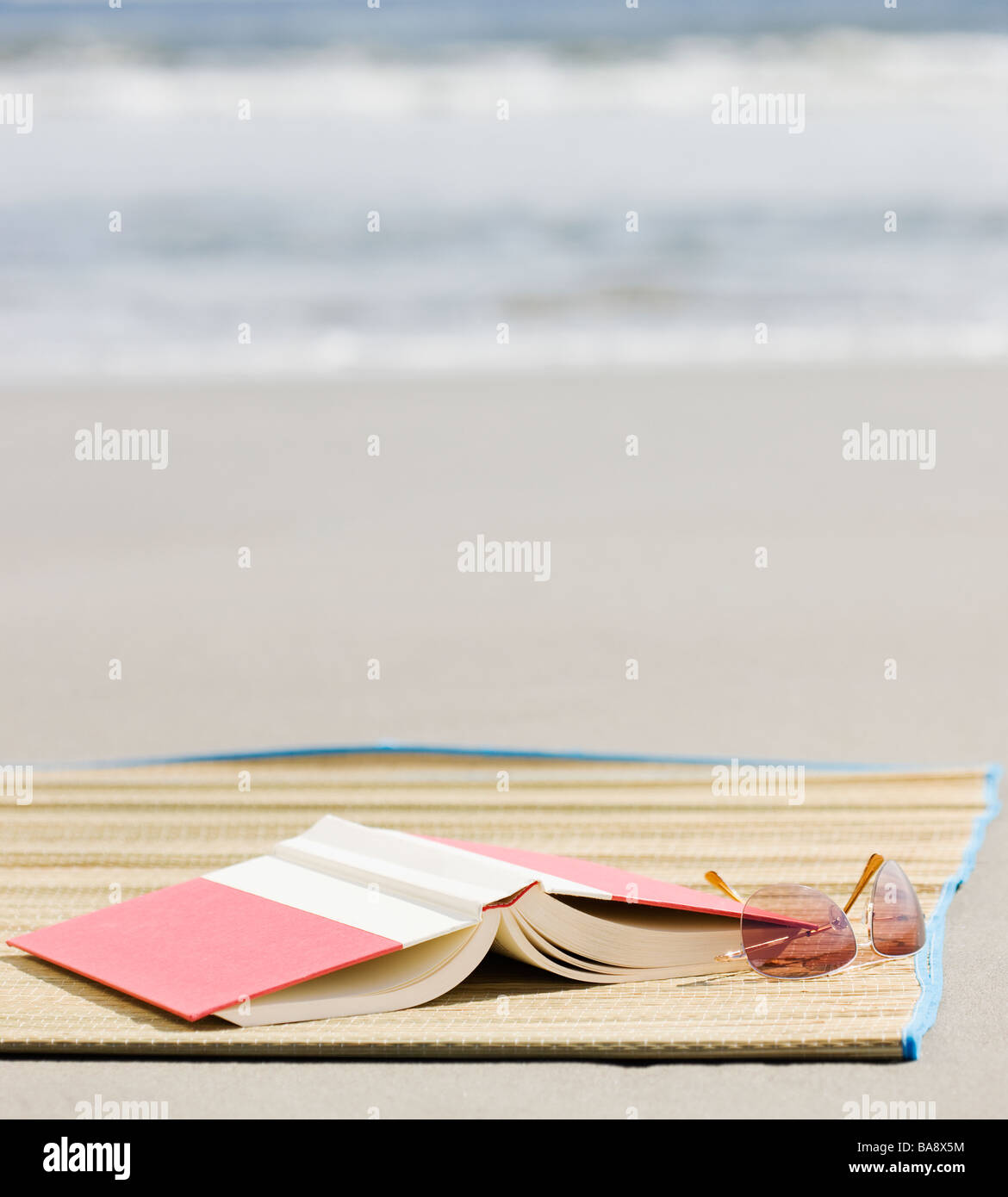 Book and sunglasses on beach Stock Photo Alamy