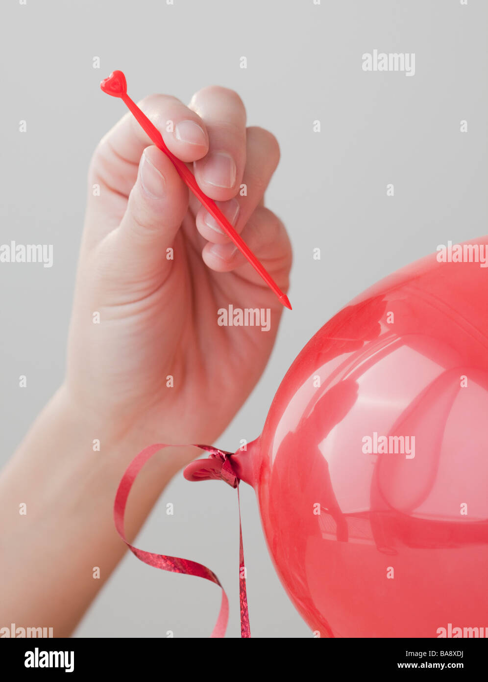 Woman popping red balloon Stock Photo