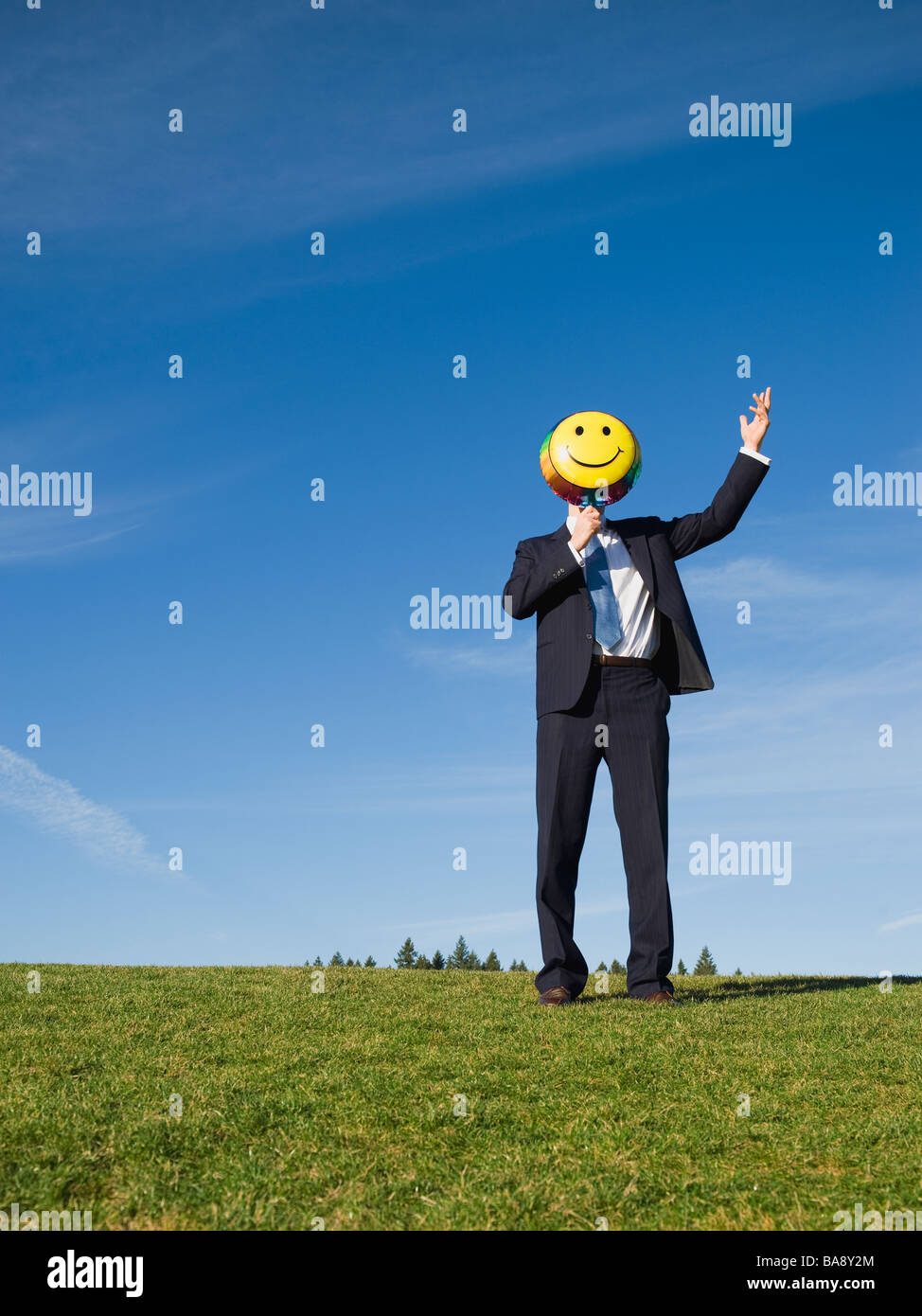 Businessman holding smiley face balloon over face Stock Photo