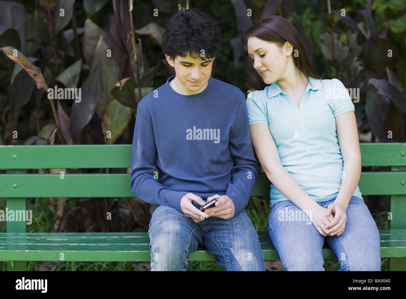 Young couple sitting on park bench Stock Photo - Alamy