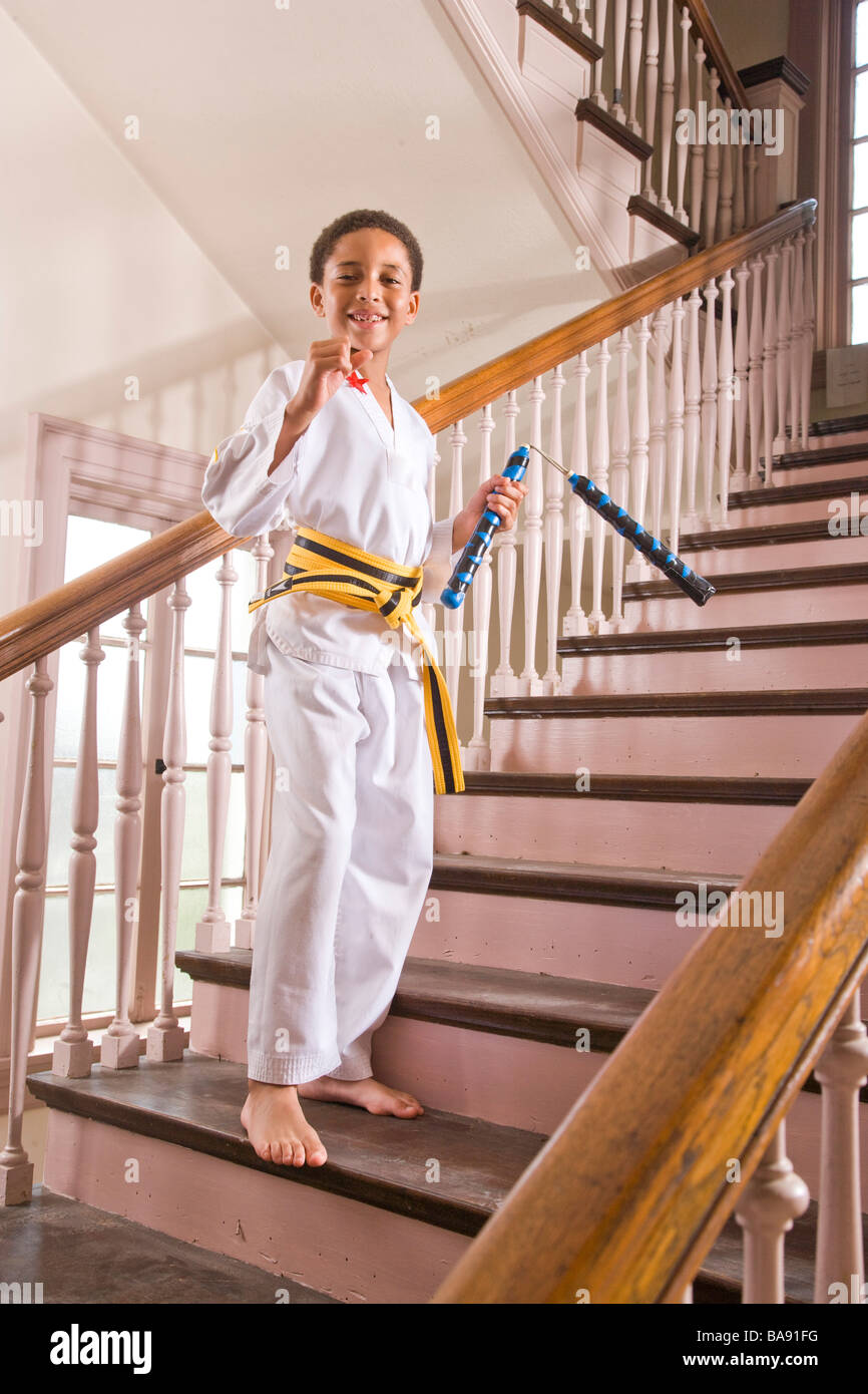 Portrait of African American boy in karate outfit standing on stairs at
