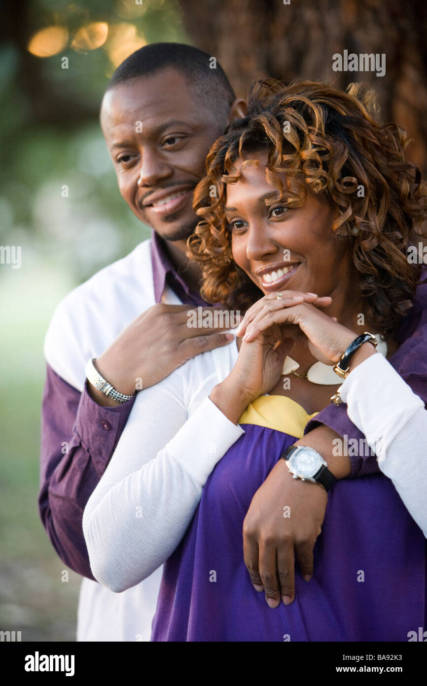Portrait of African-American couple standing near tree in park Stock ...