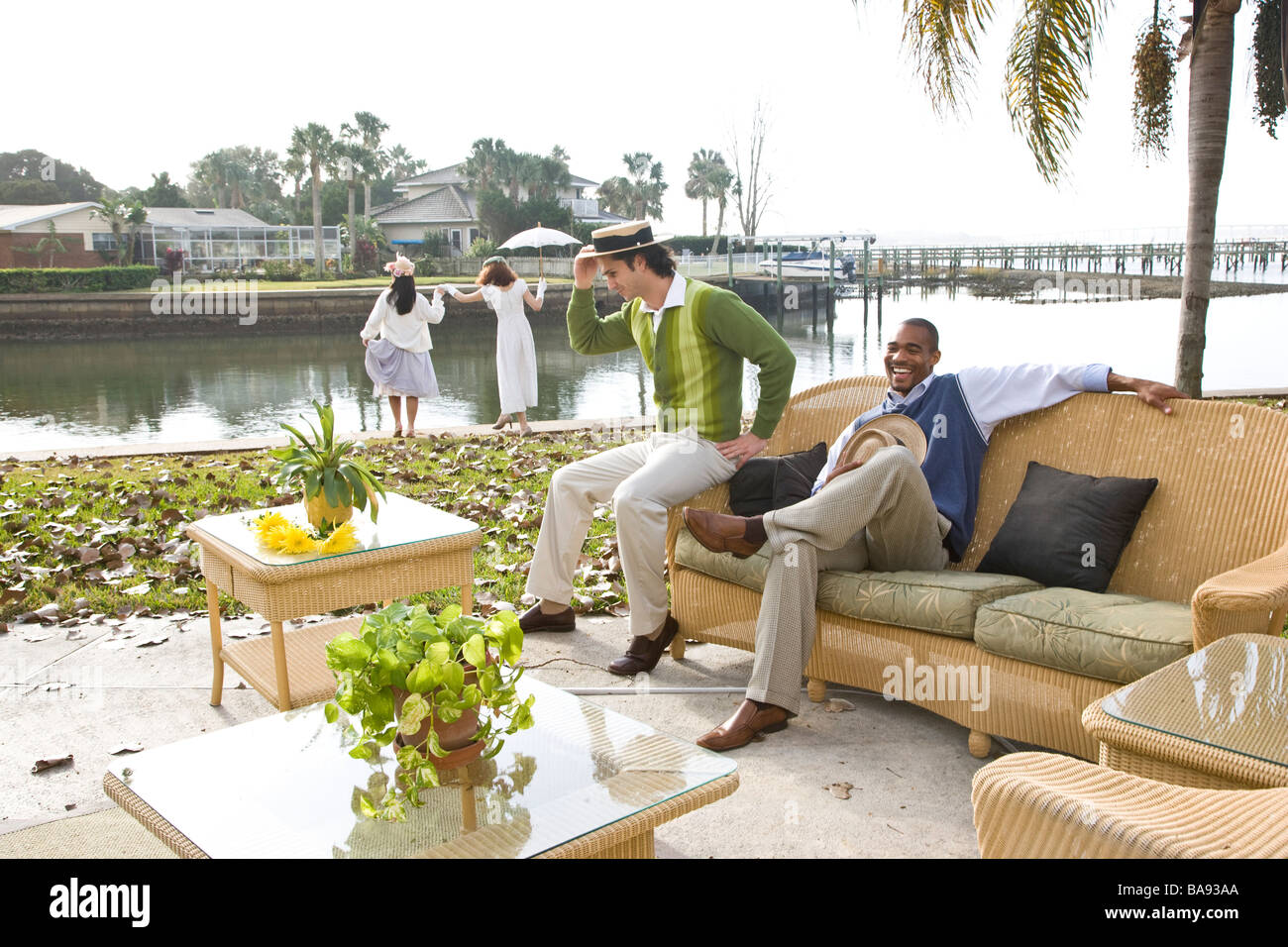 Portrait of 1920s socialite men relaxing at garden party on water's edge Stock Photo
