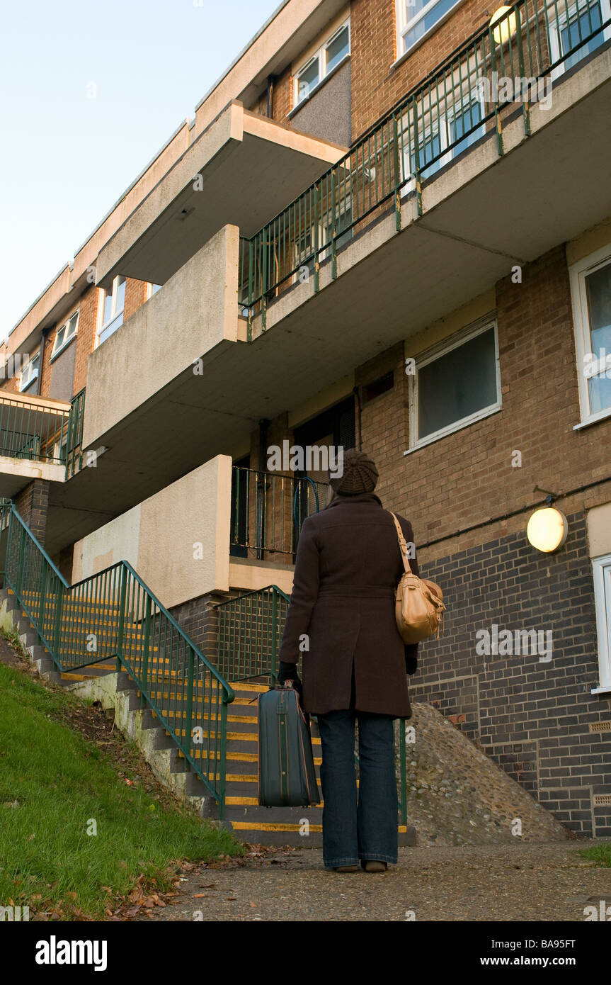 lady standing outside a block of council flats with suitcase Stock Photo