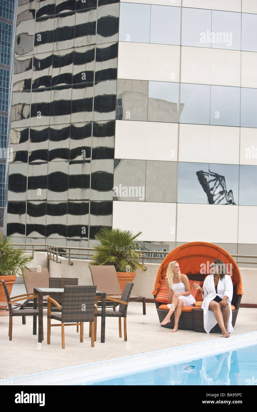 Young women relaxing near swimming pool on rooftop terrace Stock Photo ...