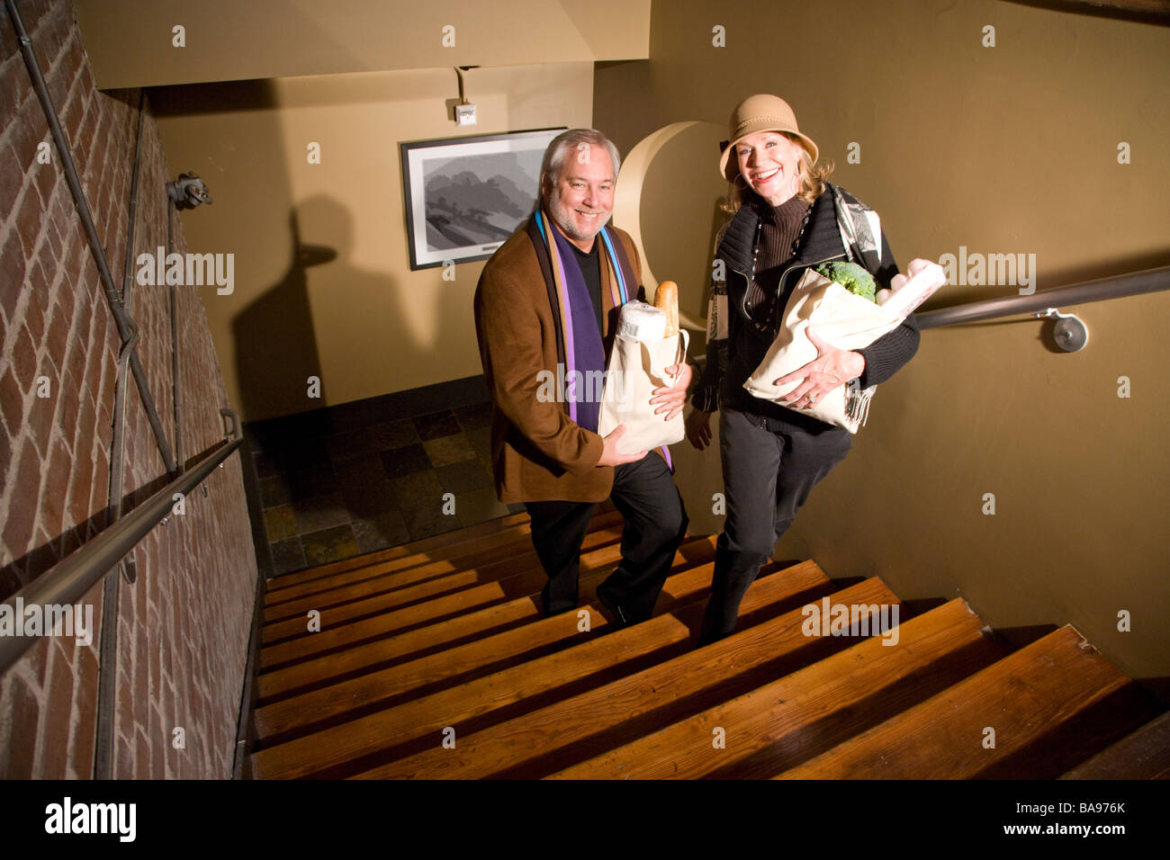Middleaged couple walking up stairs carrying grocery bags Stock Photo