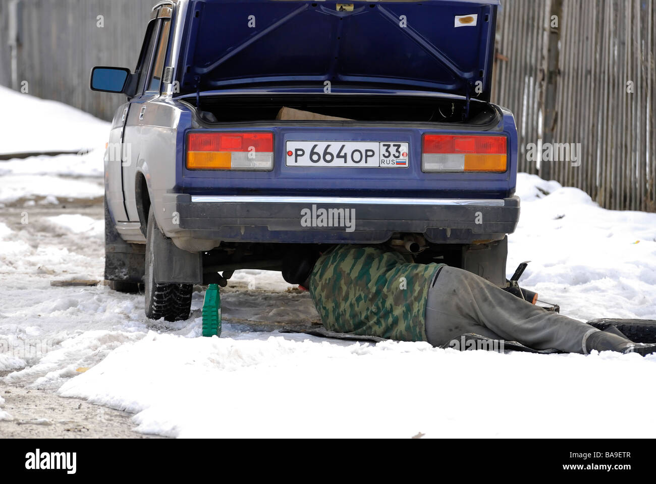 The man repairs the car laying on snow Stock Photo Alamy