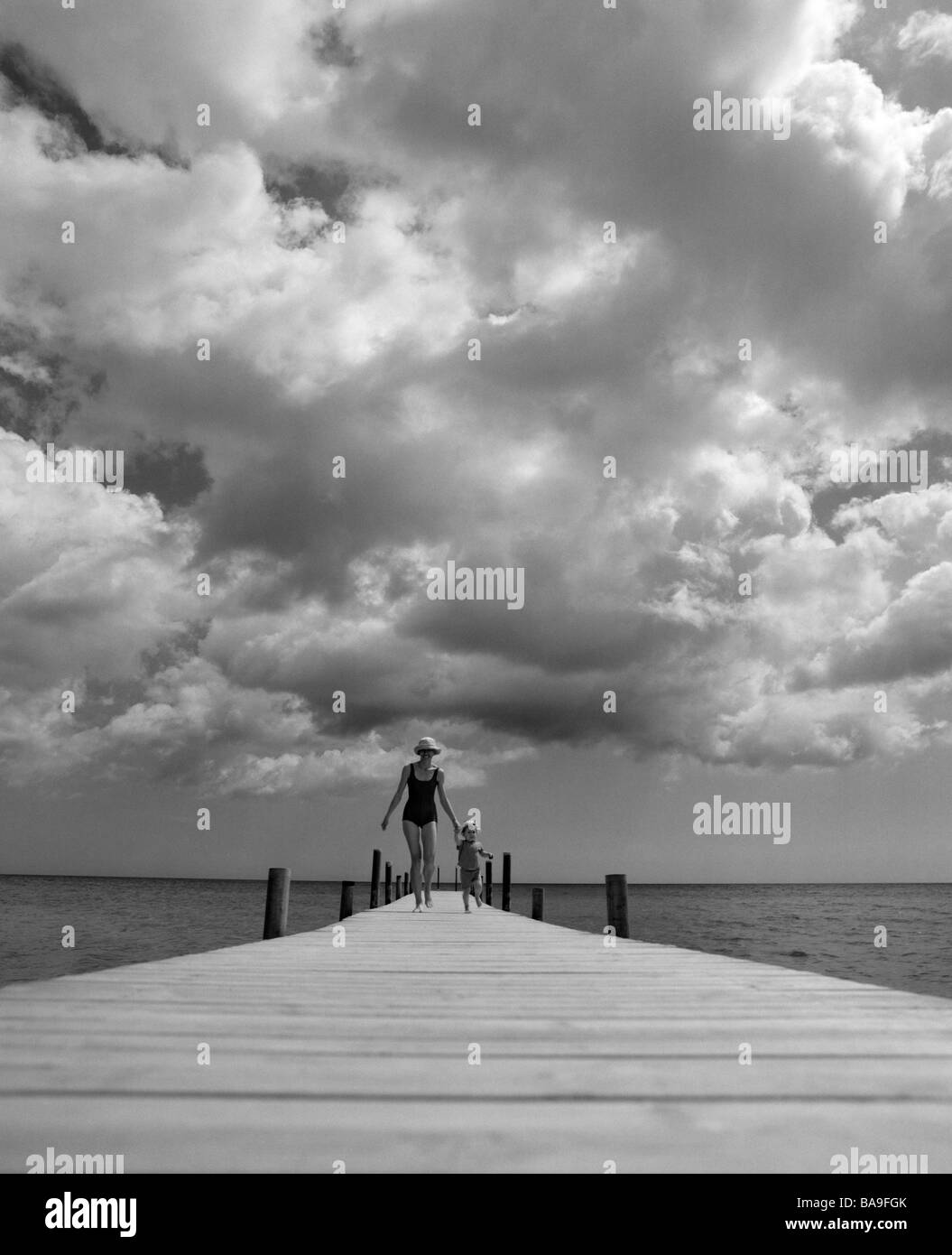 Mother and daughter running on a pier, Oland, Sweden. Stock Photo