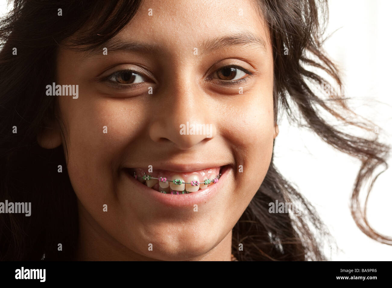 A young Hispanic girl wearing colored braces . Smiling at the camera
