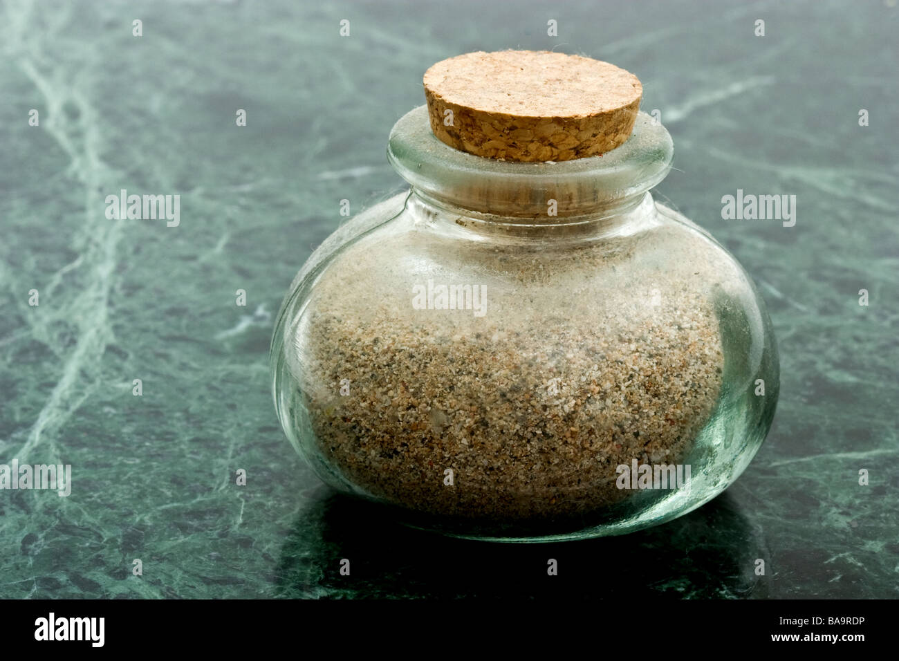 Small glass jar filled with sand with a cork stopper Stock Photo