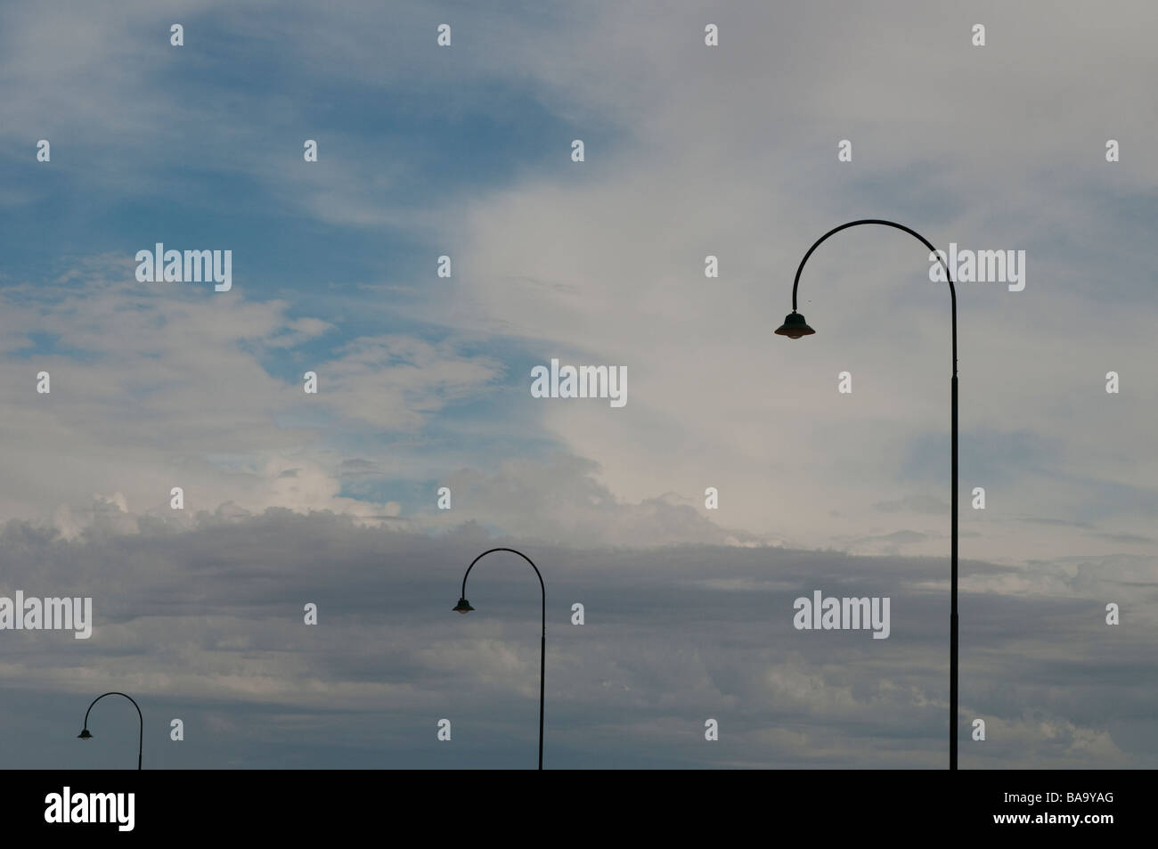 Three lampposts against the cloudy sky Stock Photo