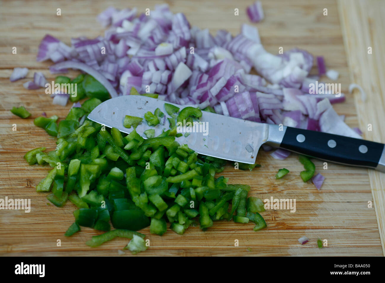 Green peppers and red onions prepared and chopped on bamboo chopping board Stock Photo