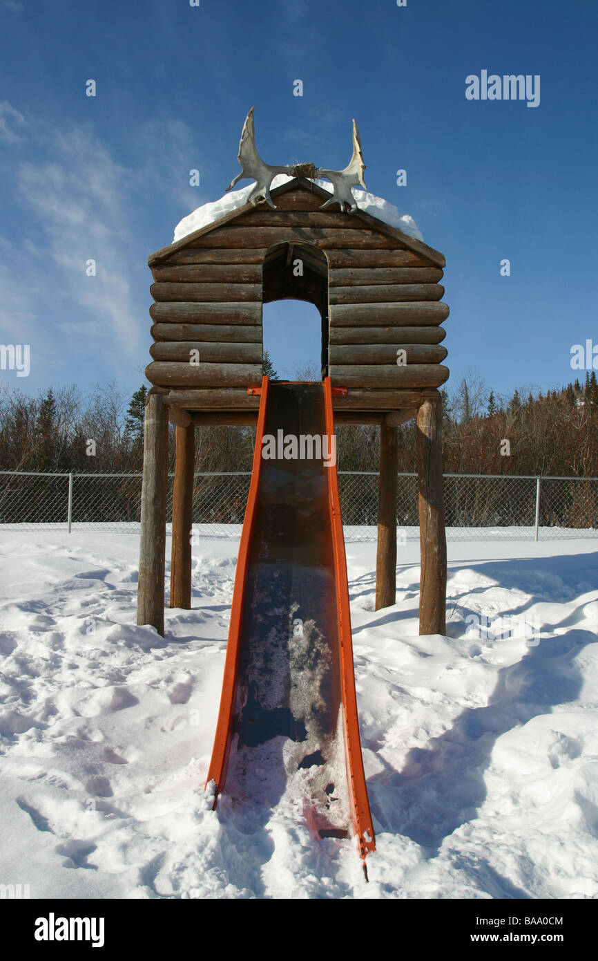 A log house and slide in a playground in the First Nation hamlet of Old Crow, Yukon Territory, Canada. Stock Photo