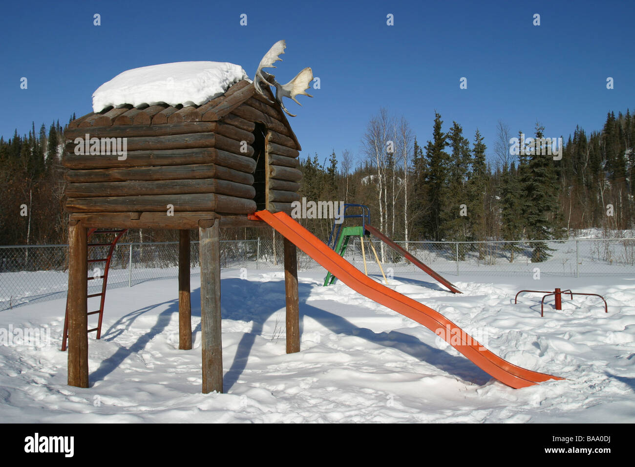 A log house and slide in a playground in the First Nation hamlet of Old Crow, Yukon Territory, Canada. Stock Photo