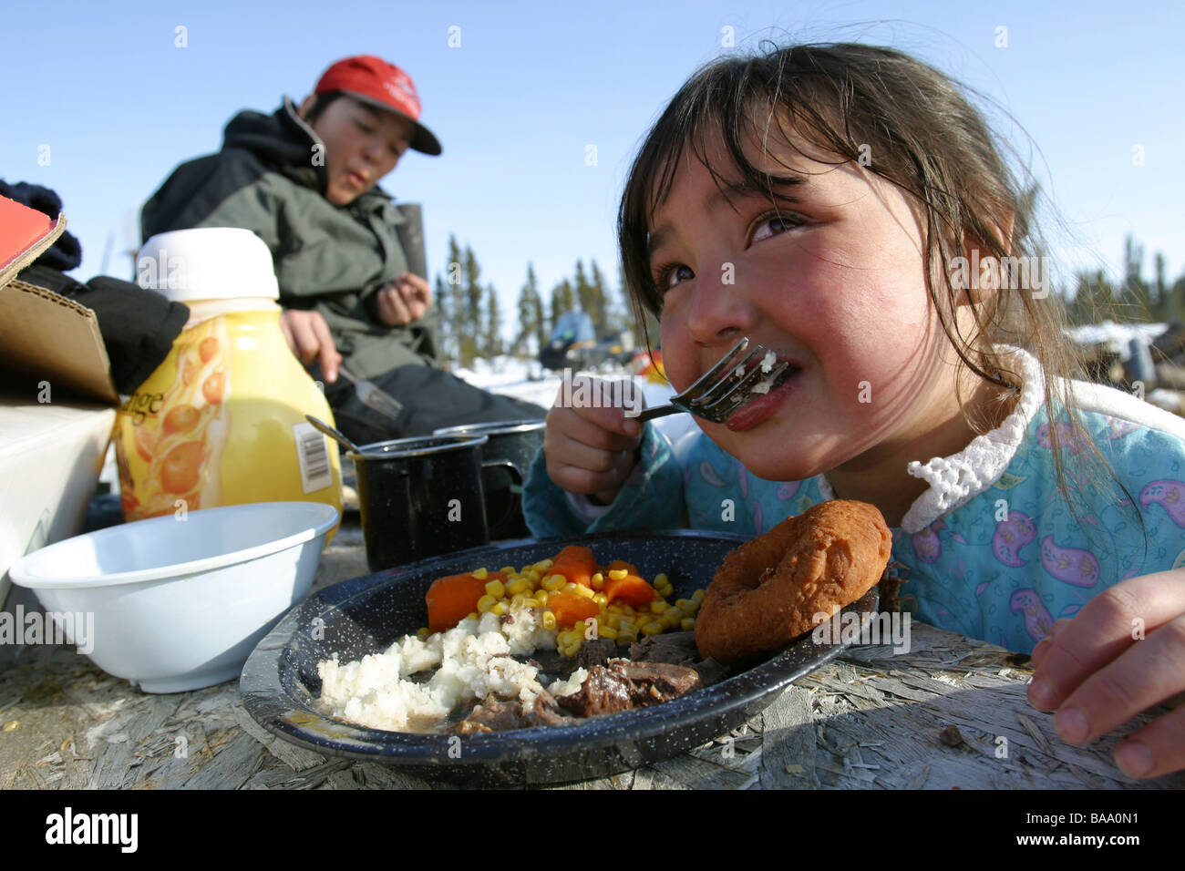 Vuntut Gwitchin First Nation children eat caribou meat at a remote Arctic winter camp near Old