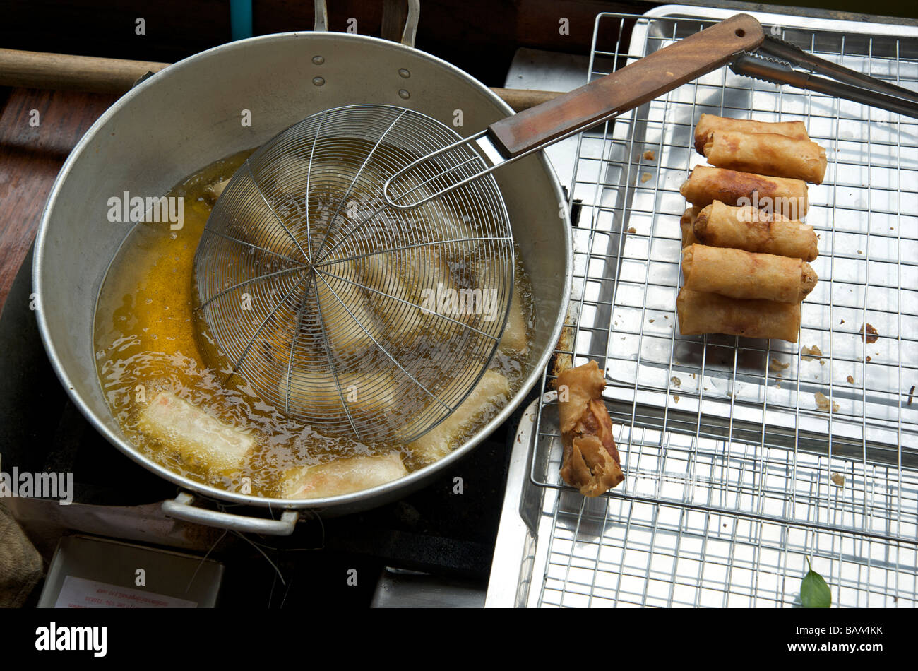 Freshly made spring rolls deep frying in a wok at the floating market
