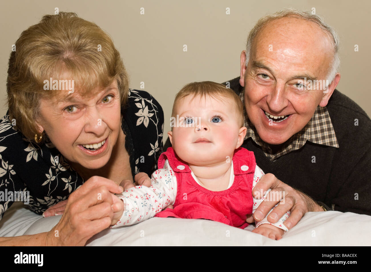 Horizontal close up portrait of proud grandparents with their cute baby granddaughter Stock Photo