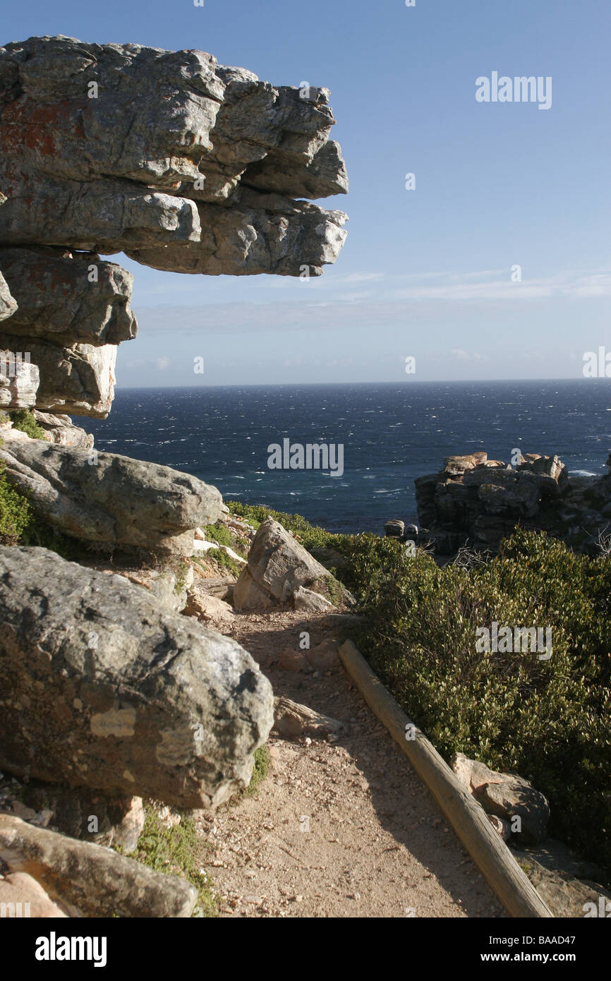Part of a walking trail that leads from Cape Point to the Cape of Good hope with a overhanging rock and a view of the ocean Stock Photo