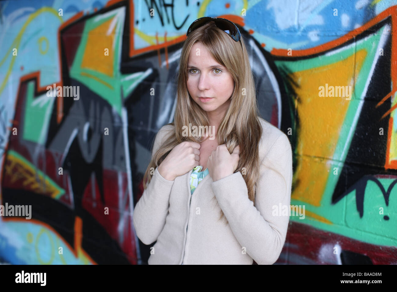 Head and shoulders shot of girl up against a graffiti sprayed wall Stock Photo