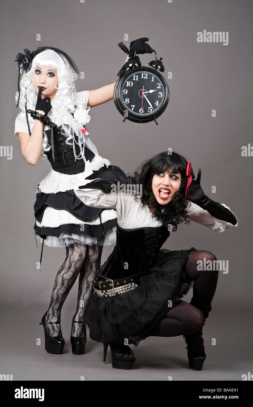 Gothic dressed teenager holding a very noisy alarm clock Stock Photo