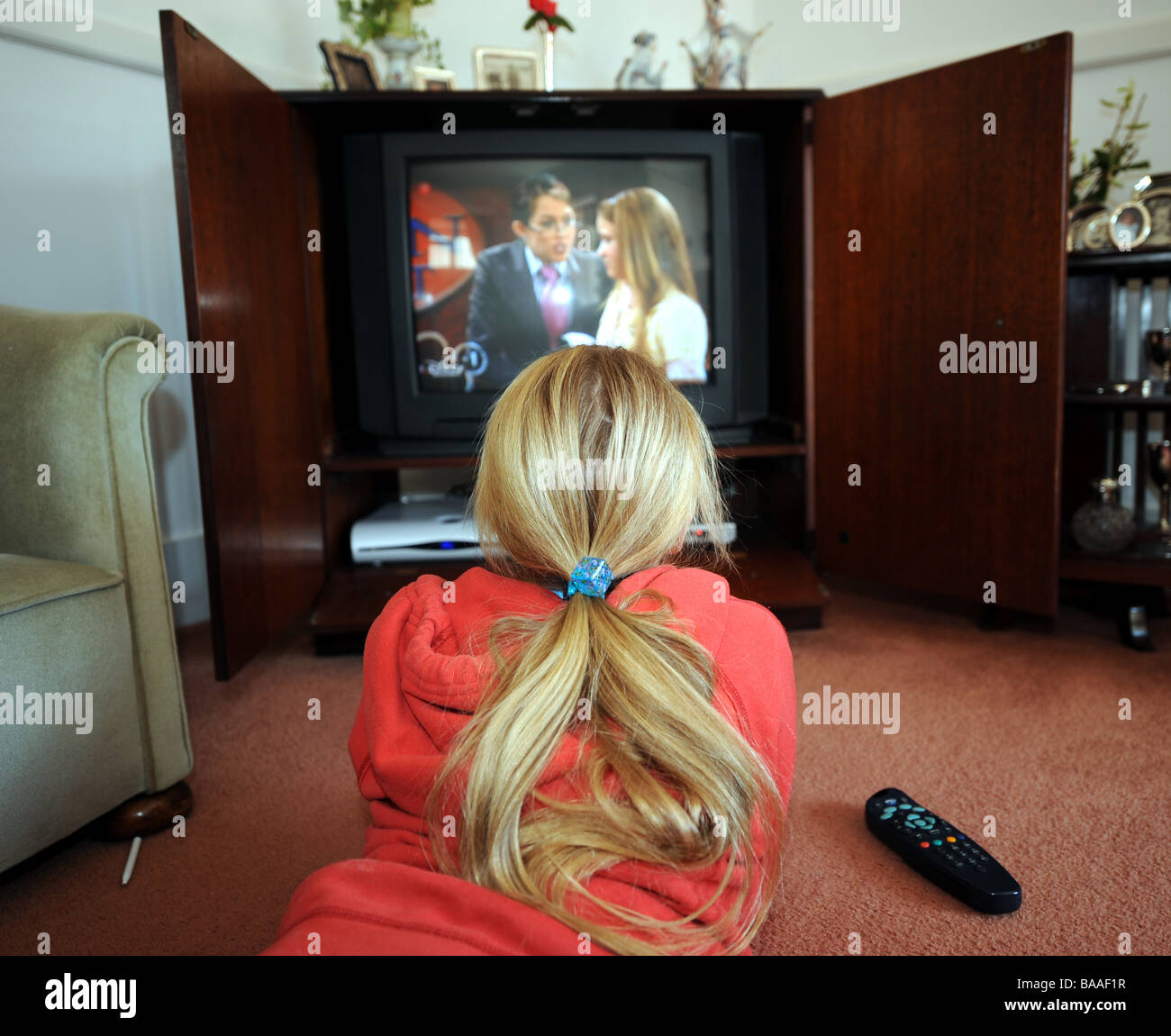 Young 9 yr old girl watches television as she draws in her sketchbook