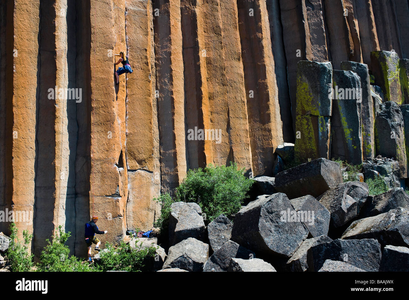 A young woman rock climbing while a mid adult man belays at Trout Creek