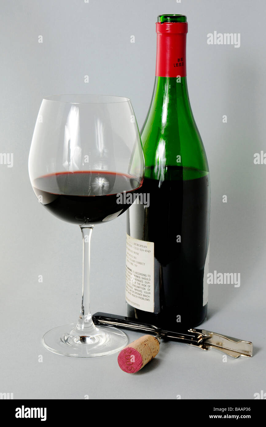 Bottle of red wine with half full glass and corkscrew with cork Stock Photo