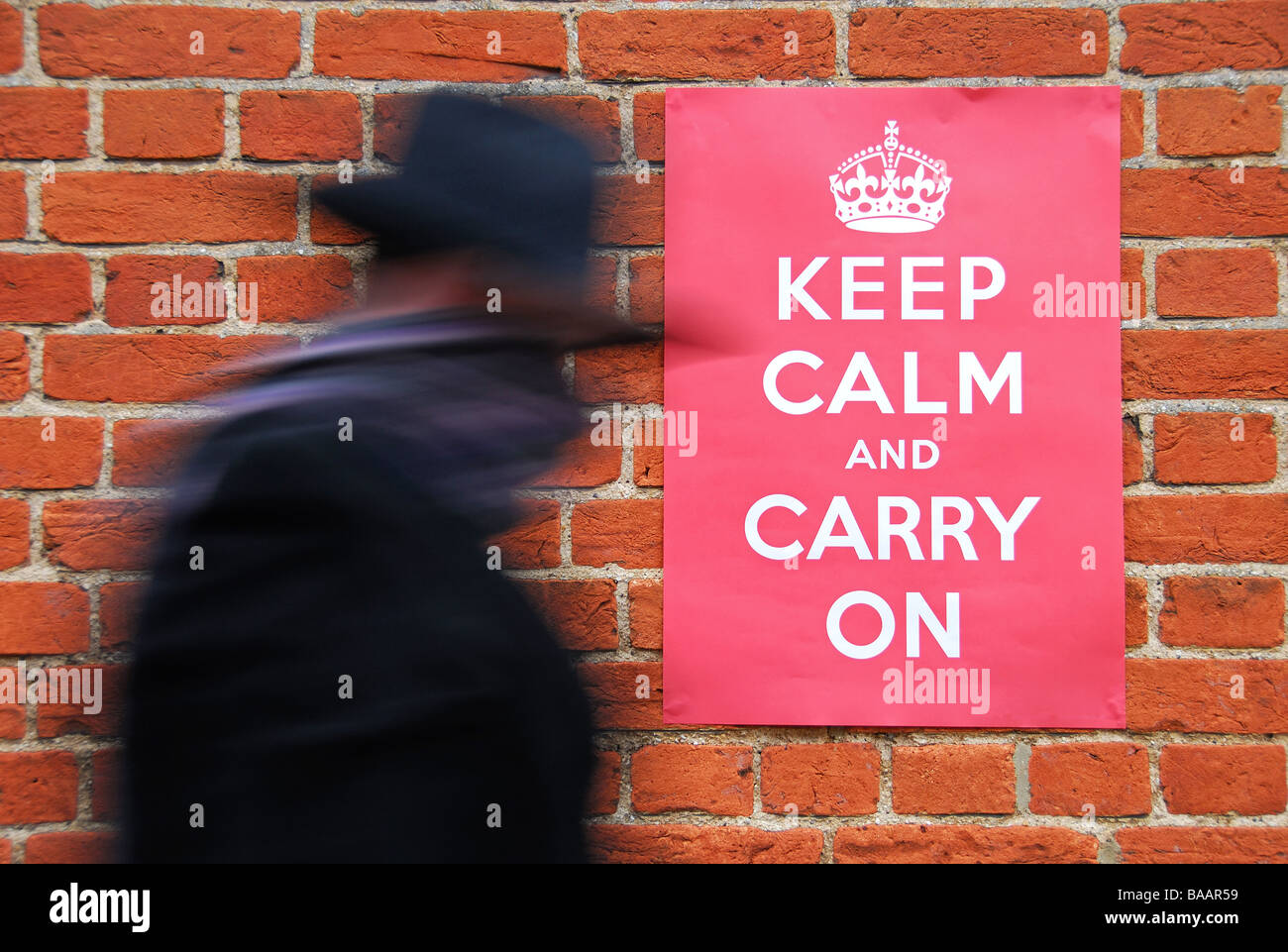 Man walking past a Second World War poster urging people to keep calm and carry on. Stock Photo