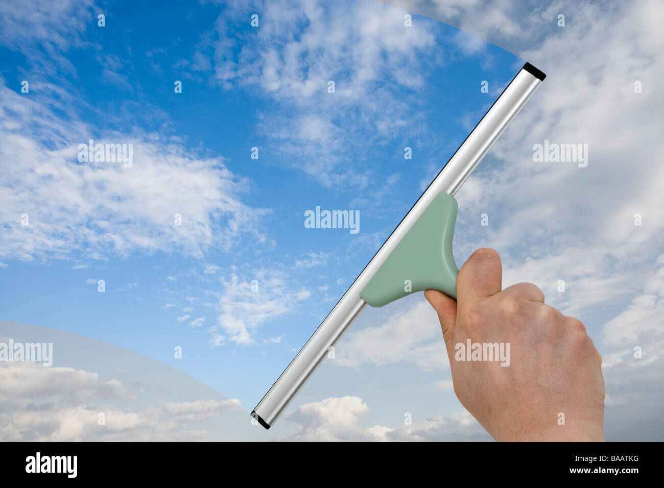 hand cleaning a window with a squeegee, turning dull sky into blue Stock Photo