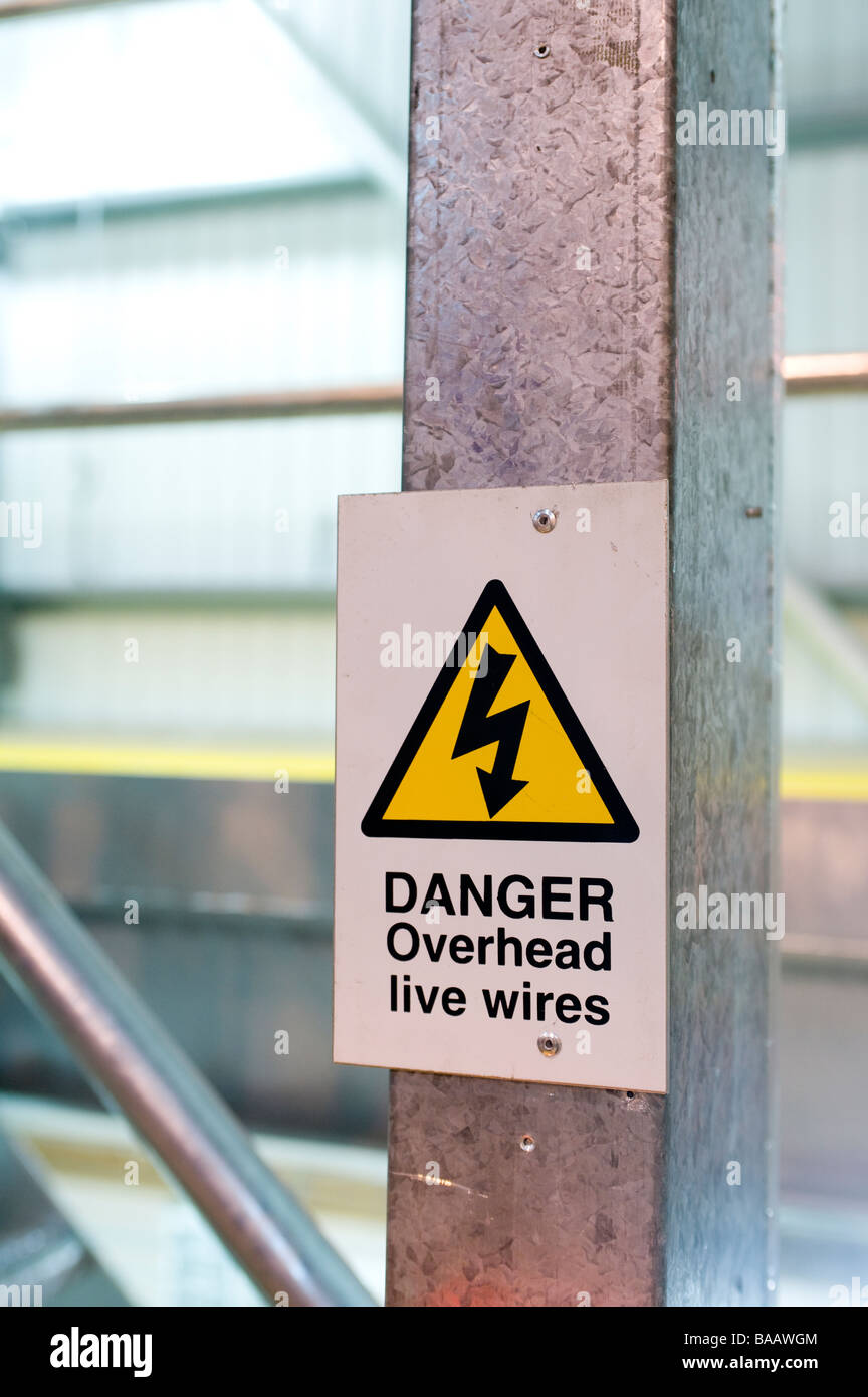 Yellow triangle health and safety sign warning of danger overhead live electrical wires Stock Photo